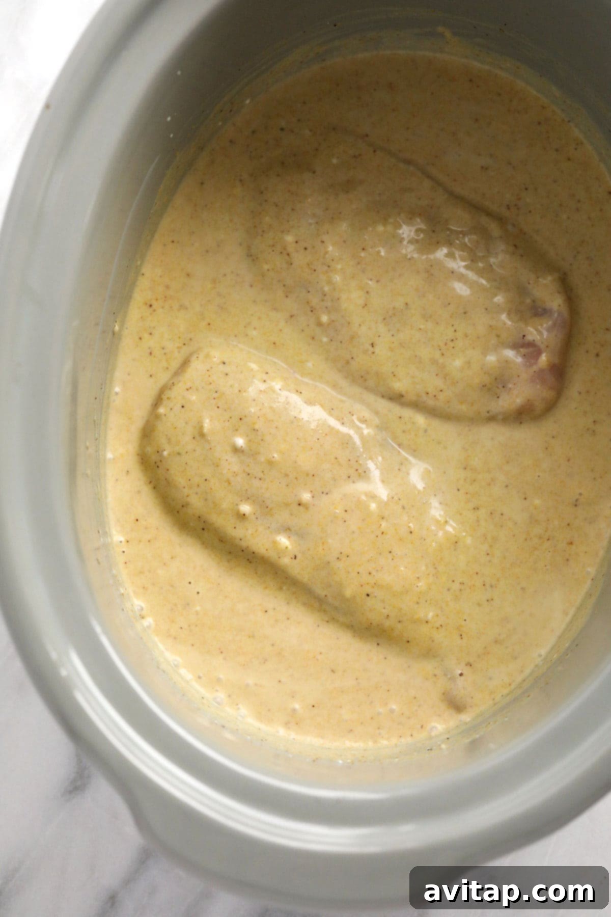 Aromatic Coconut Curry Chicken 5 Chicken breasts simmering in a rich coconut curry sauce within a slow cooker.