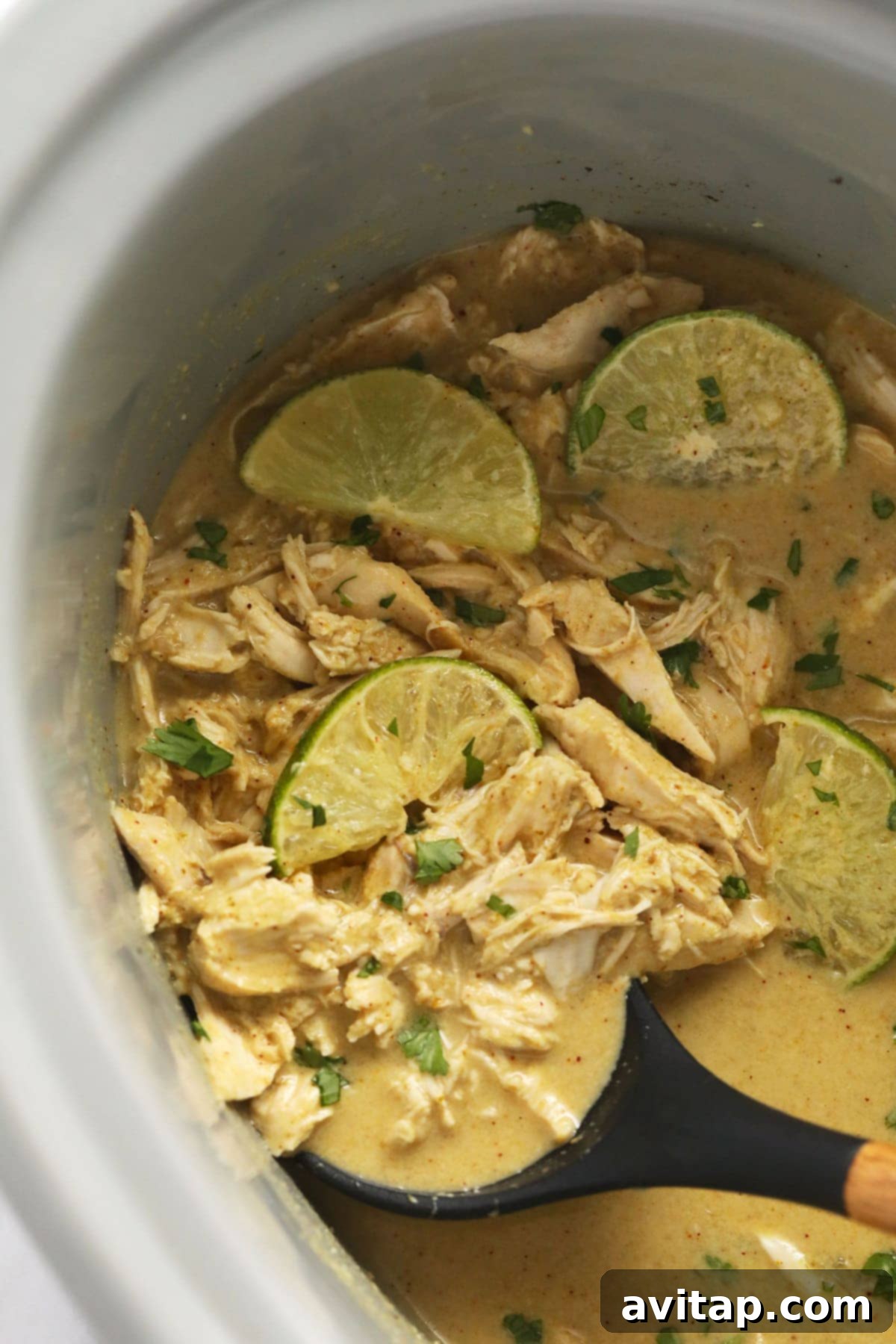Aromatic Coconut Curry Chicken 7 Slow cooker coconut curry chicken garnished with fresh lime wedges and cilantro, ready for serving.