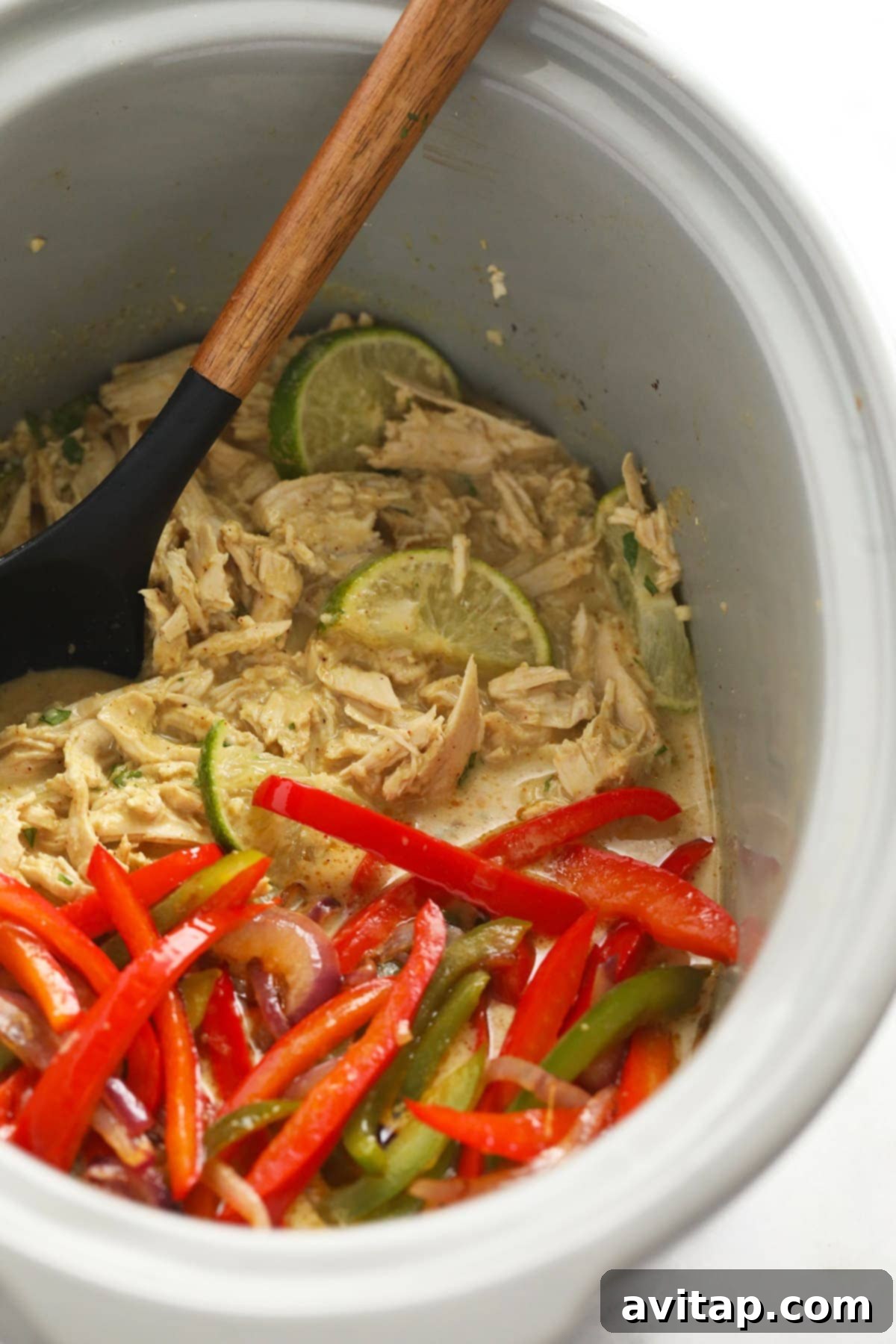 Aromatic Coconut Curry Chicken 8 Slow cooker filled with coconut curry chicken, mixed with vibrant peppers and onions.