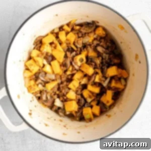 Butternut squash and other vegetables simmering in wine, deglazing the pot for rich flavor.