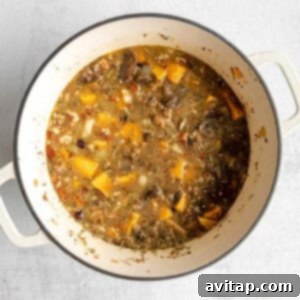 All stuffing ingredients, including quinoa, fruits, and nuts, mixed together in a Dutch oven before baking.