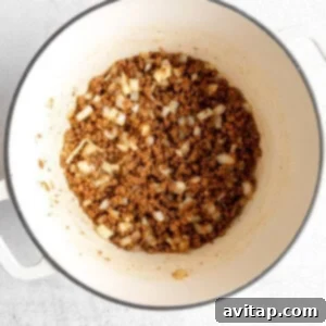 Sautéing ground meat and onions in a Dutch oven until fragrant and lightly browned.