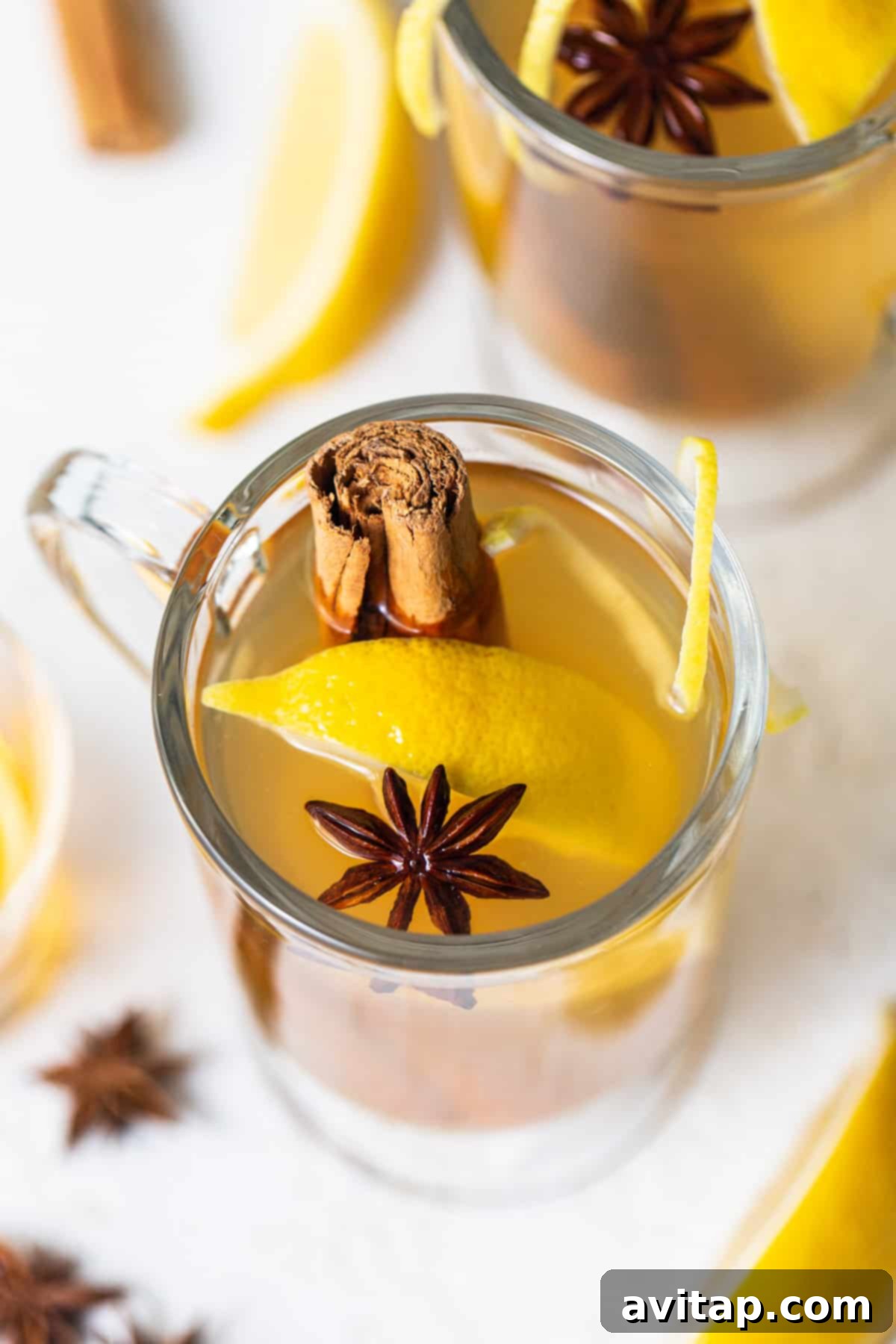 A steaming cup of Maple Hot Toddy garnished with cinnamon sticks and star anise, exuding warmth and inviting comfort.