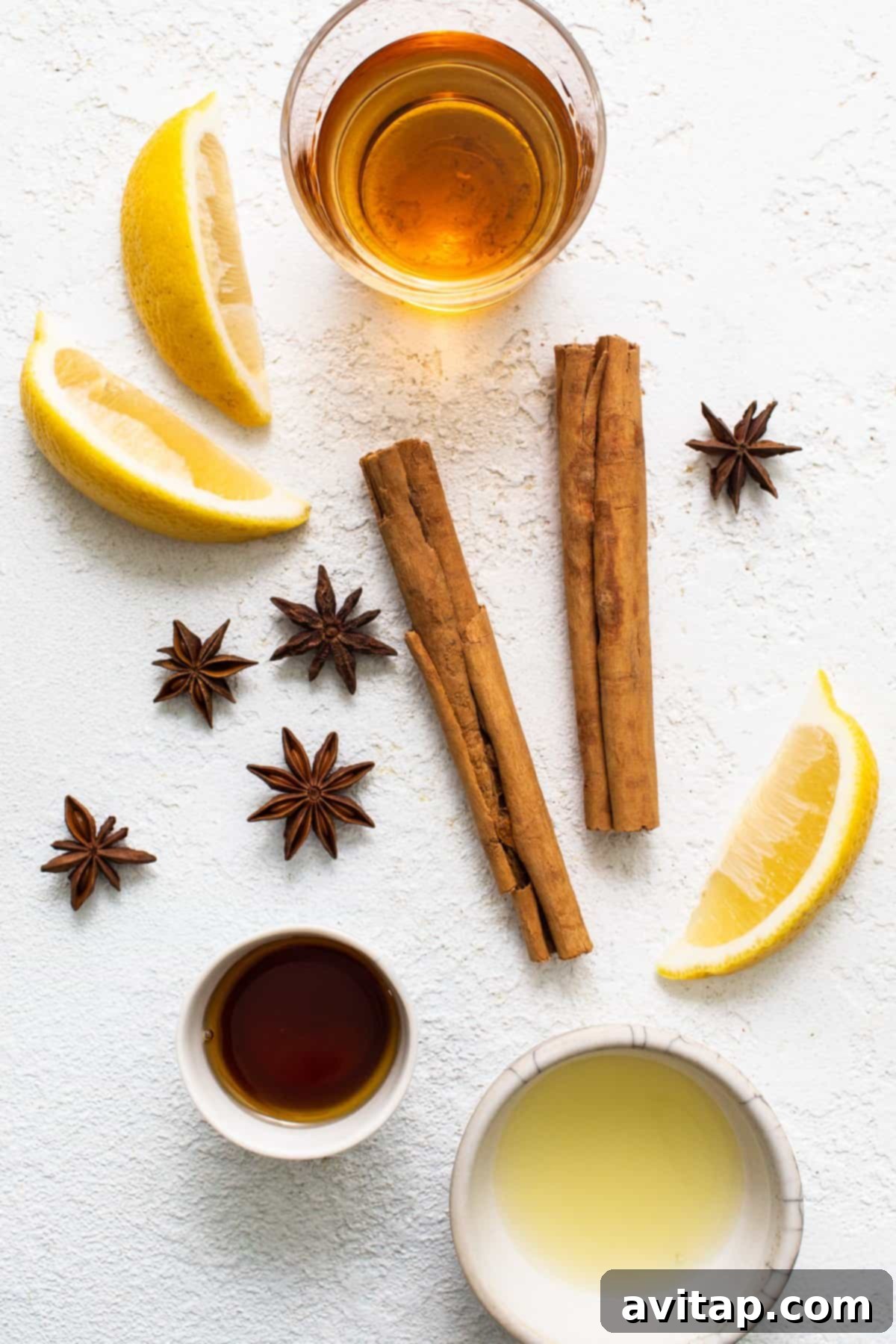 A thoughtful arrangement of cinnamon sticks, fresh lemon, star anise, and a golden dollop of honey, showcasing essential hot toddy ingredients.