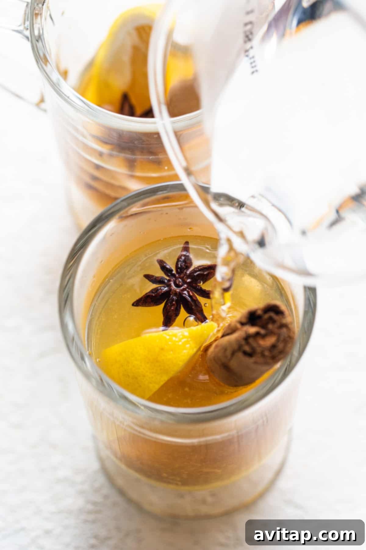 A pristine glass featuring a vibrant lemon slice and a star anise pod, ready for a hot toddy.