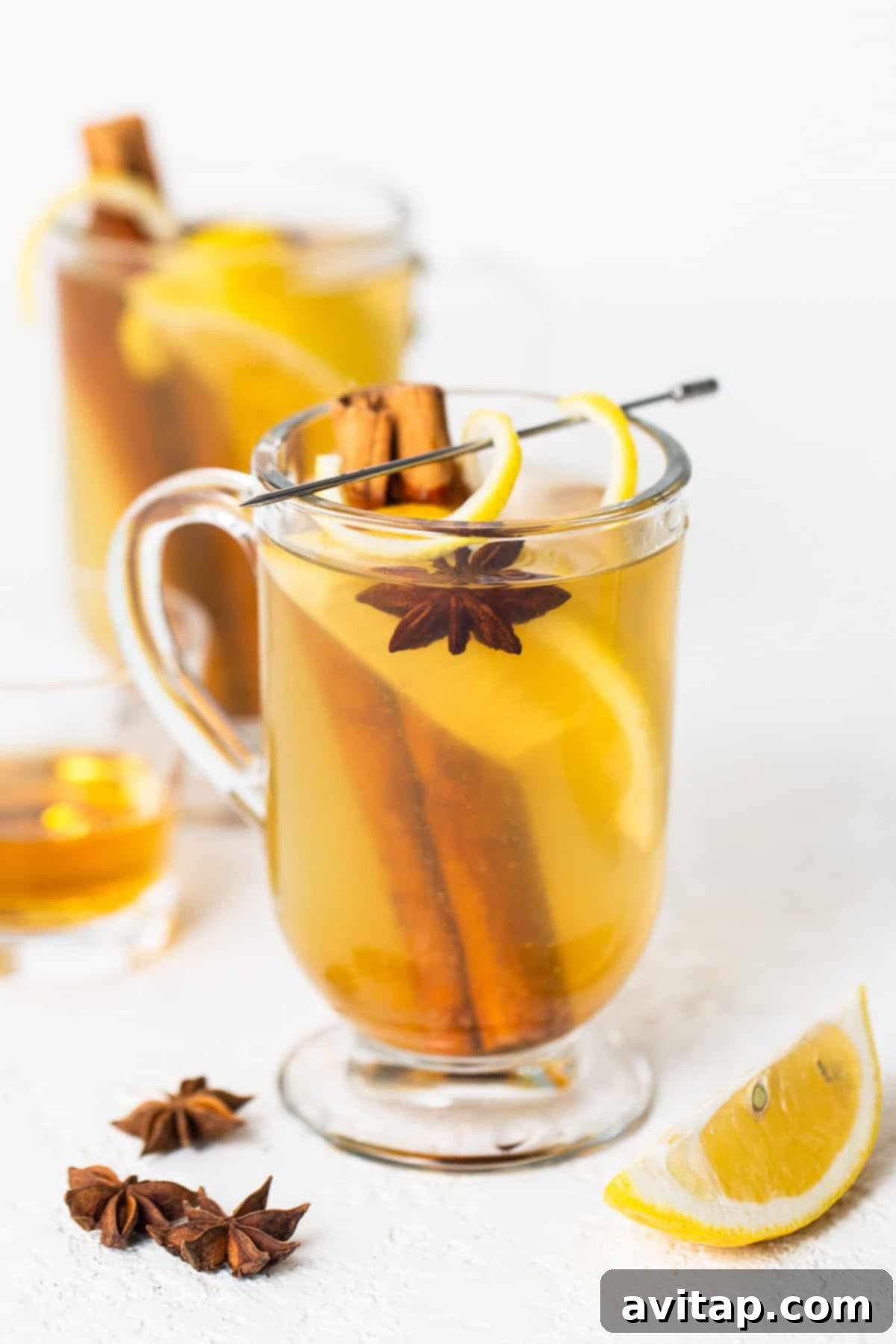 A beautifully presented cup of mulled cider, adorned with fragrant cinnamon sticks and star anise, inviting warmth.
