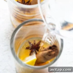 Hot water being poured into a glass containing lemon and star anise for a hot toddy.