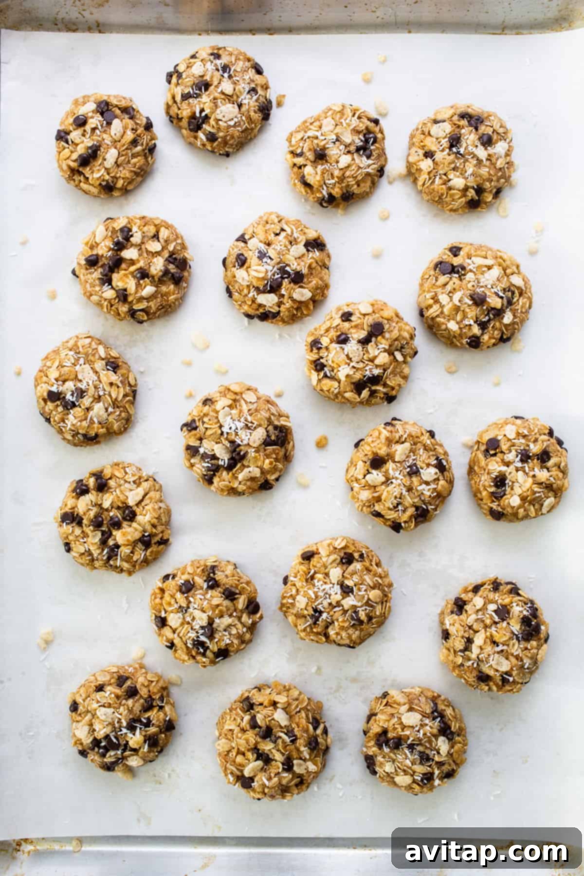 Freshly baked chocolate chip cookies cooling on a baking sheet, with a few sprinkles of sea salt visible.