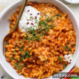 A bowl of creamy One-Pot Lasagna Pasta with meat sauce and a dollop of whipped cottage cheese.