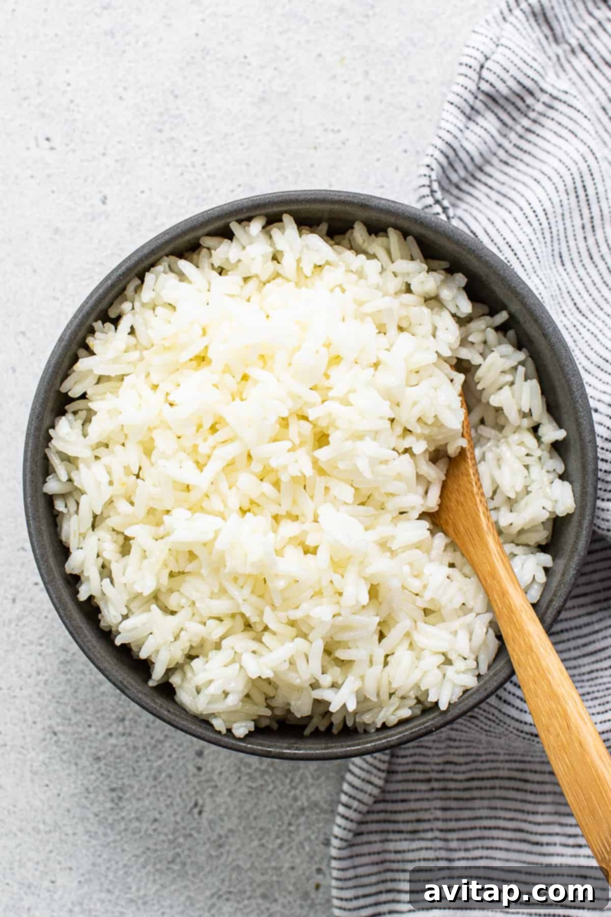 Fluffy Instant Pot White Rice 2 A perfectly cooked bowl of fluffy white rice, ready to be served, with a wooden spoon for scooping.