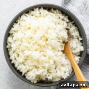 White rice in a bowl with a wooden spoon, showcasing its perfect texture.