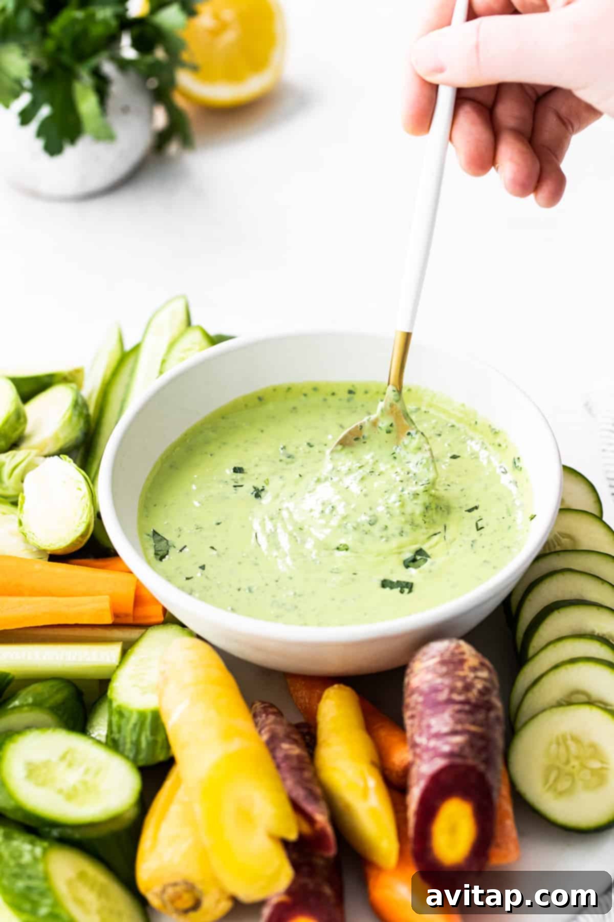 A spoon scooping creamy Green Goddess Dressing from a bowl, showcasing its rich texture.