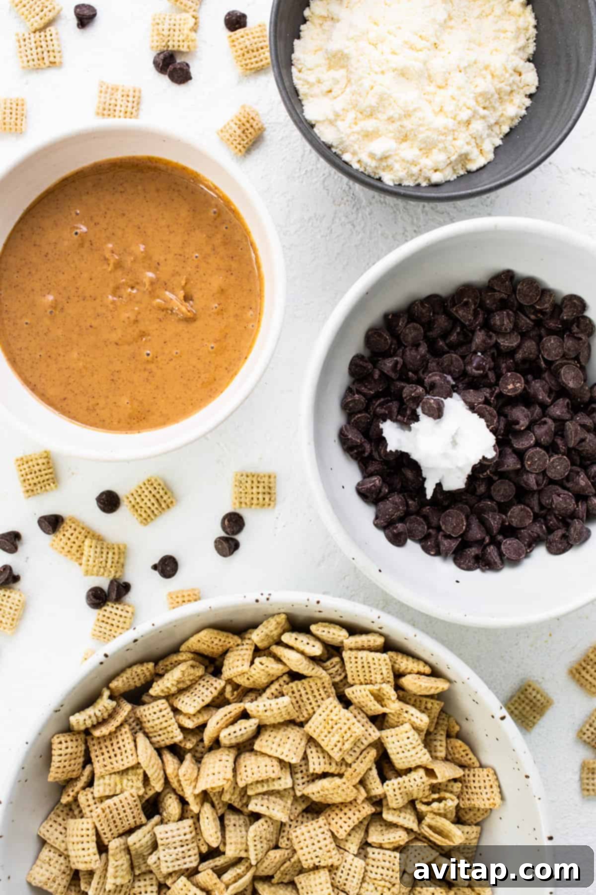 A large bowl containing un-coated Chex cereal and a scattering of semi-sweet chocolate chips, preparing for the melting process.