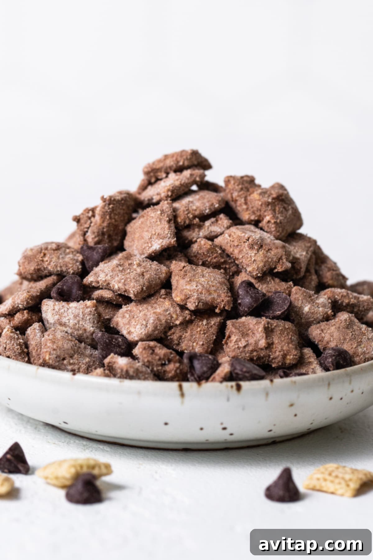 A simple white bowl filled with chocolate protein puppy chow, presented elegantly on a clean white background.
