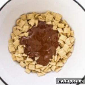 A bowl filled with chocolate and chex mix, partially coated.