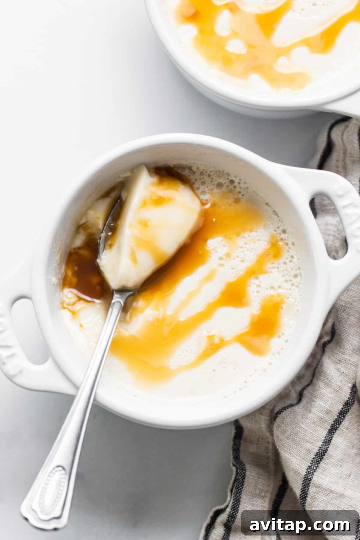 A bowl of creamer panna cotta with caramel sauce and a spoon, ready to be enjoyed.