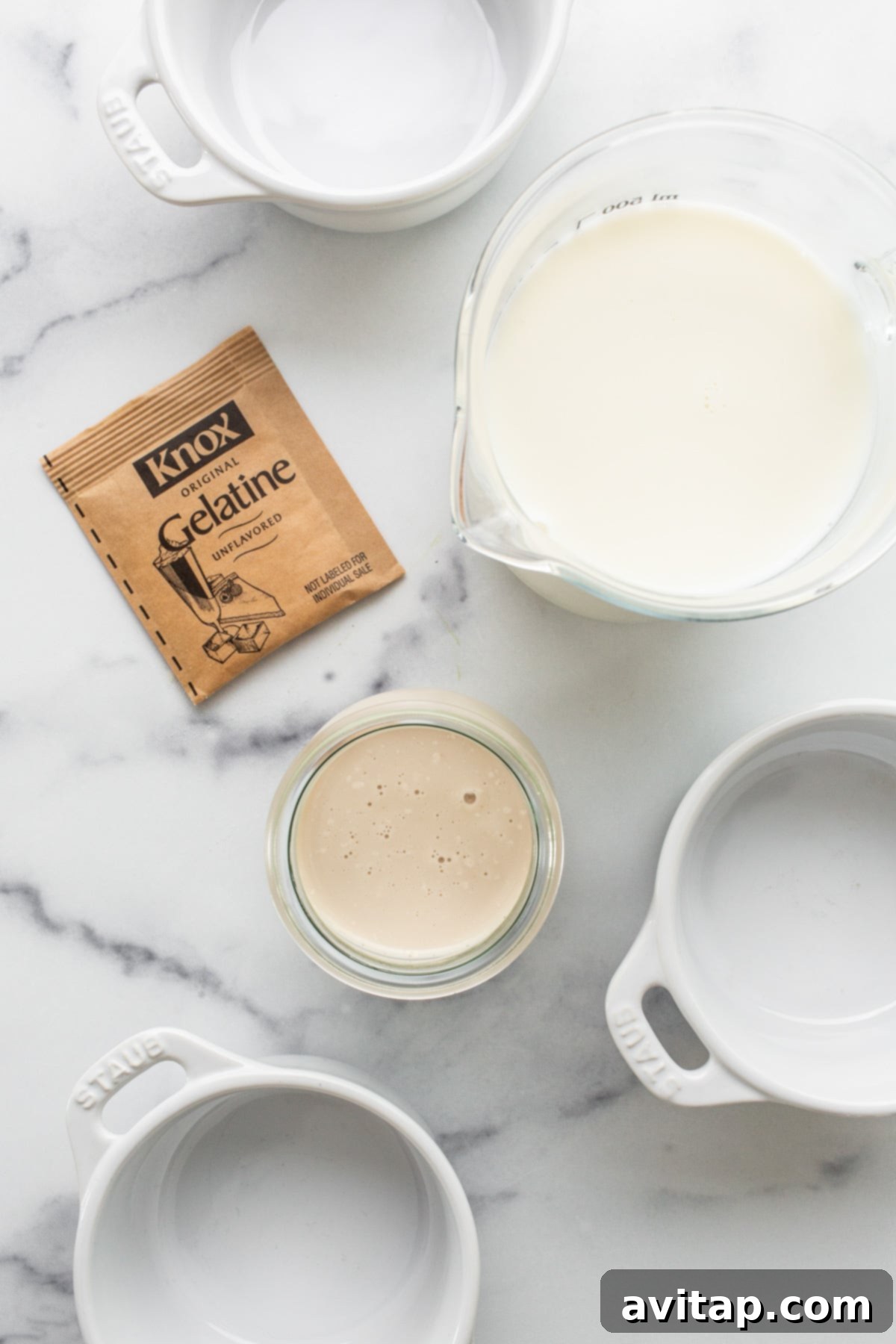 A selection of ingredients for panna cotta including milk, a packet of gelatin, and a spoon.