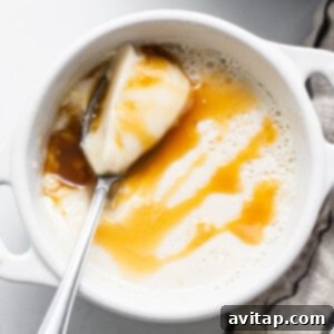 A bowl of creamer panna cotta with caramel sauce and a spoon.