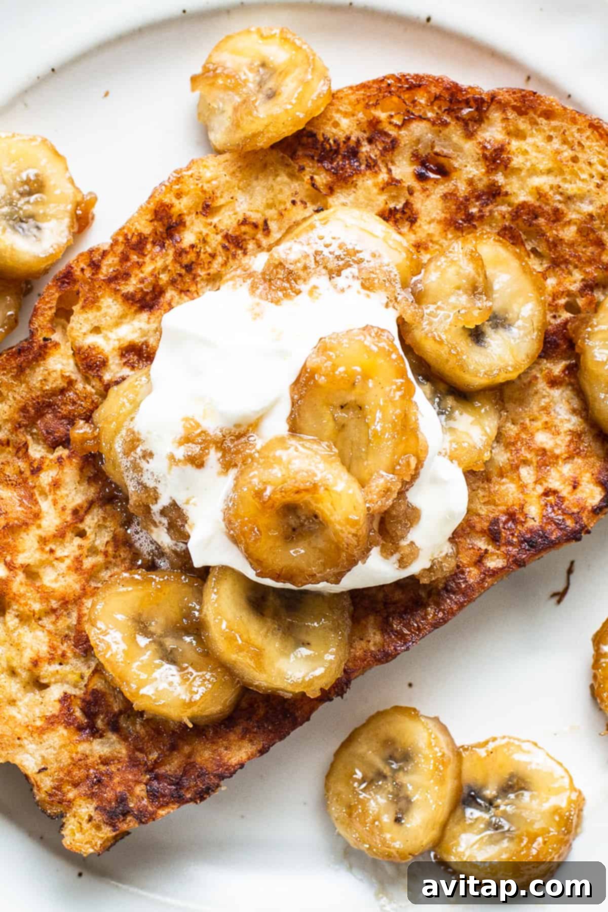 A plate of french toast with banana slices and whipped cream, garnished with mint.