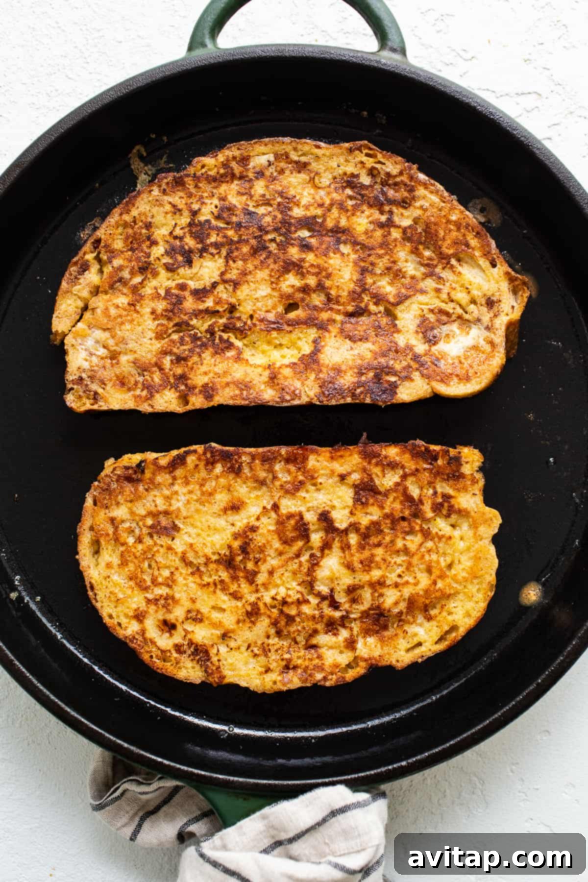 Two slices of french toast in a skillet, golden brown and perfectly cooked.