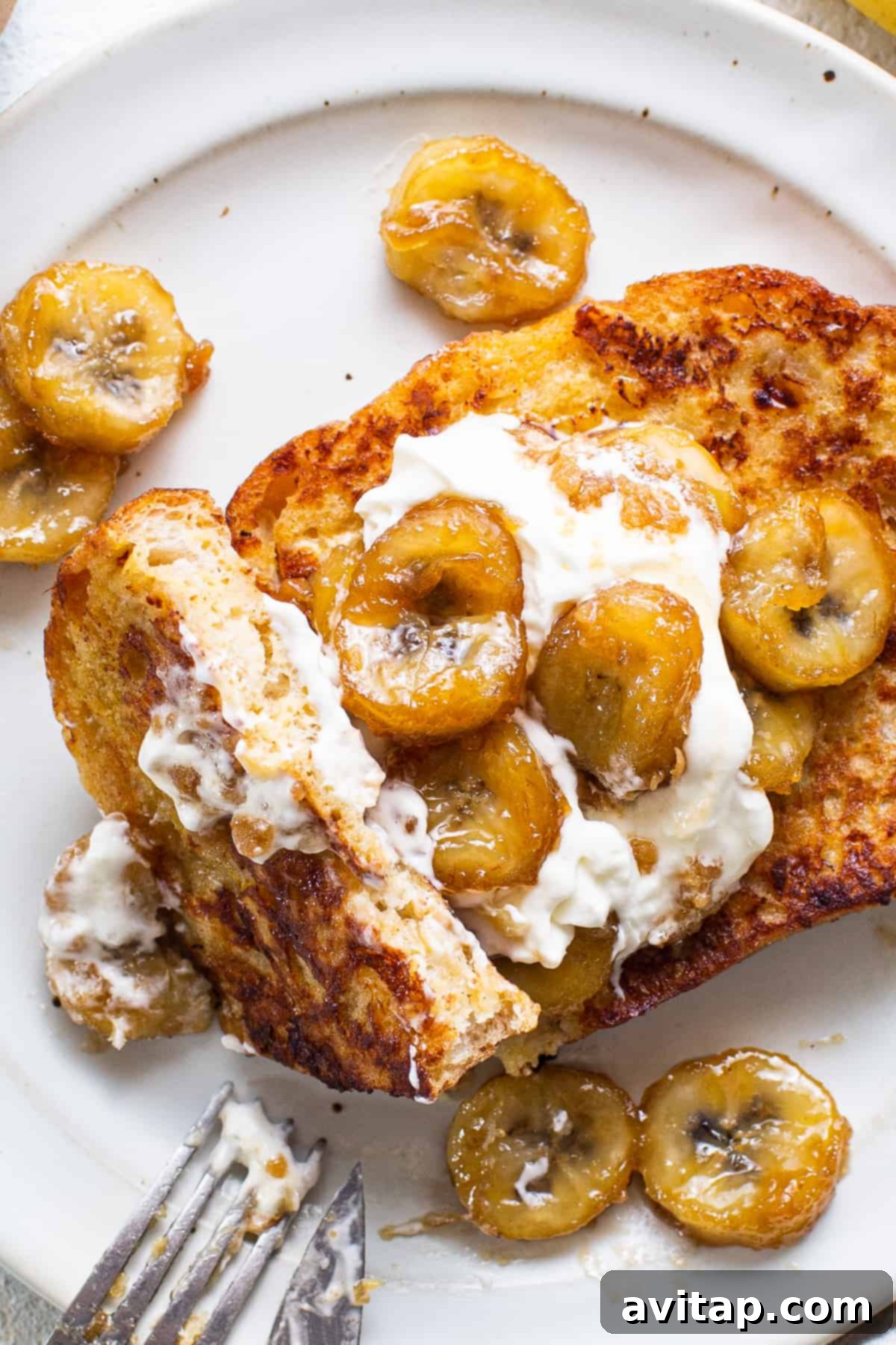 French toast with bananas and whipped cream, garnished with a sprinkle of cinnamon.