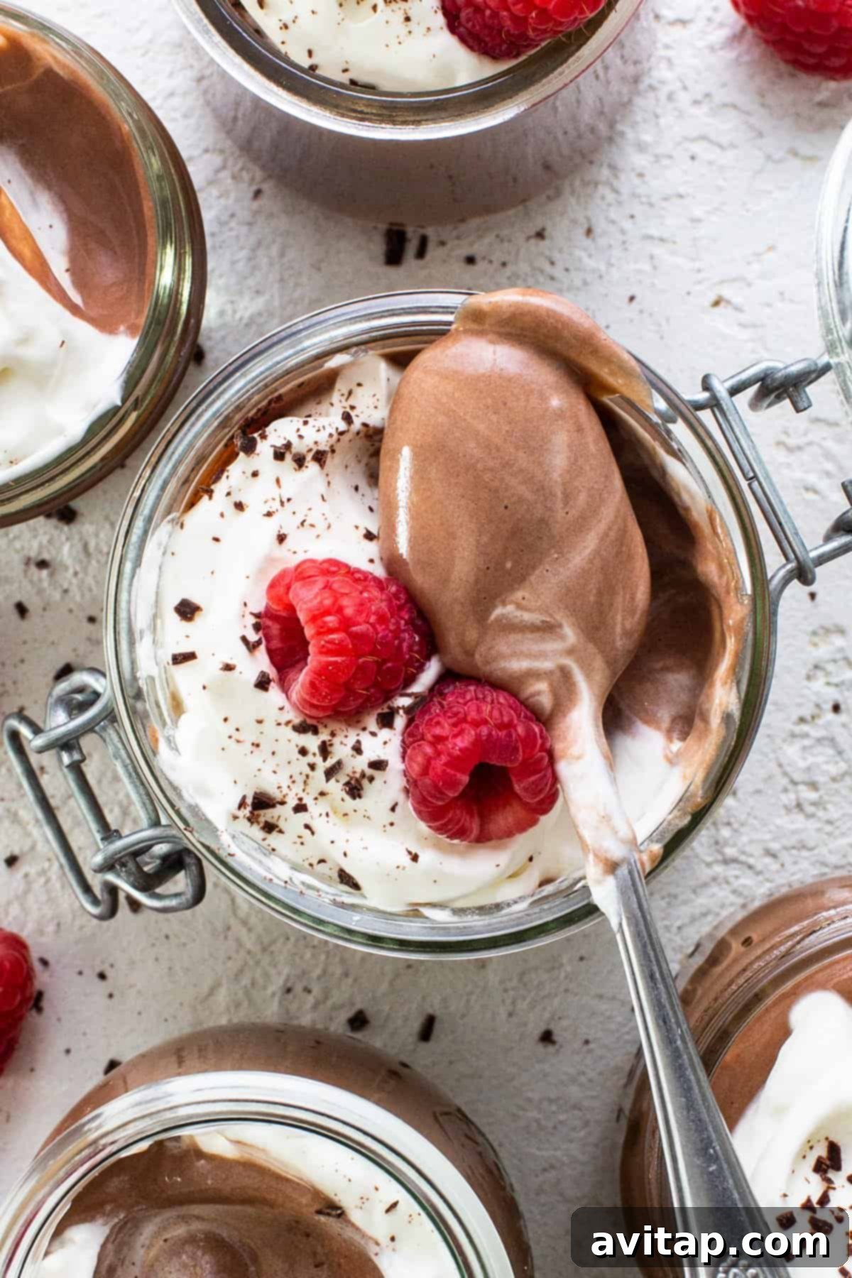 Chocolate mousse in jars with whipped cream and raspberries.