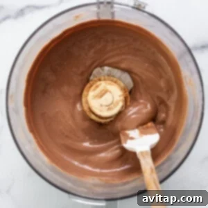 Chocolate ganache in a mixing bowl with a wooden spoon.