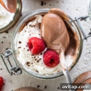 Chocolate mousse in jars with whipped cream and raspberries.