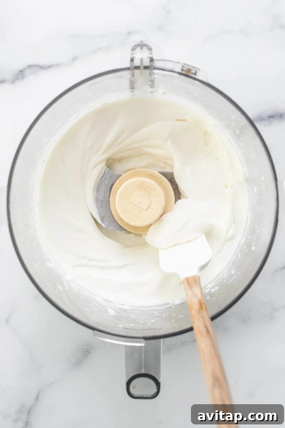 Whipped cream in a mixing bowl with a wooden spoon.