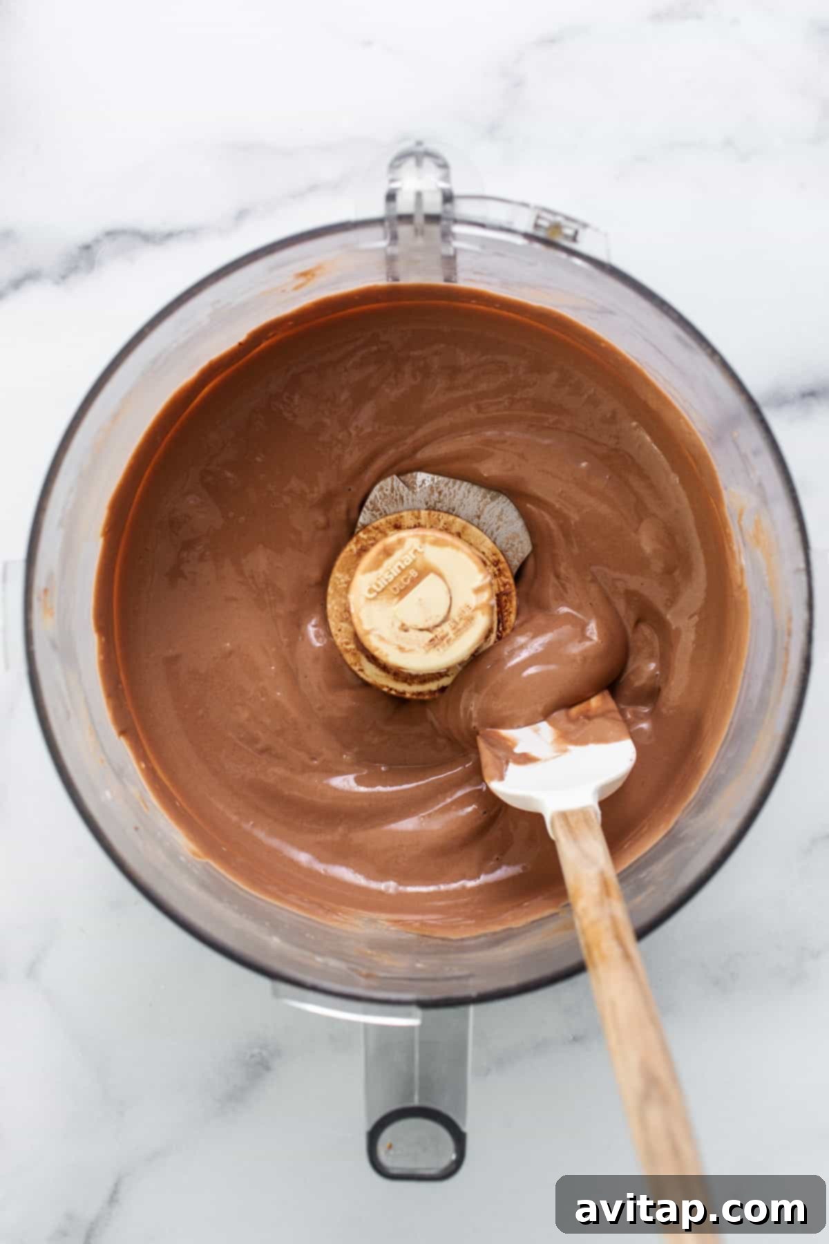 Chocolate ganache in a mixing bowl with a wooden spoon.