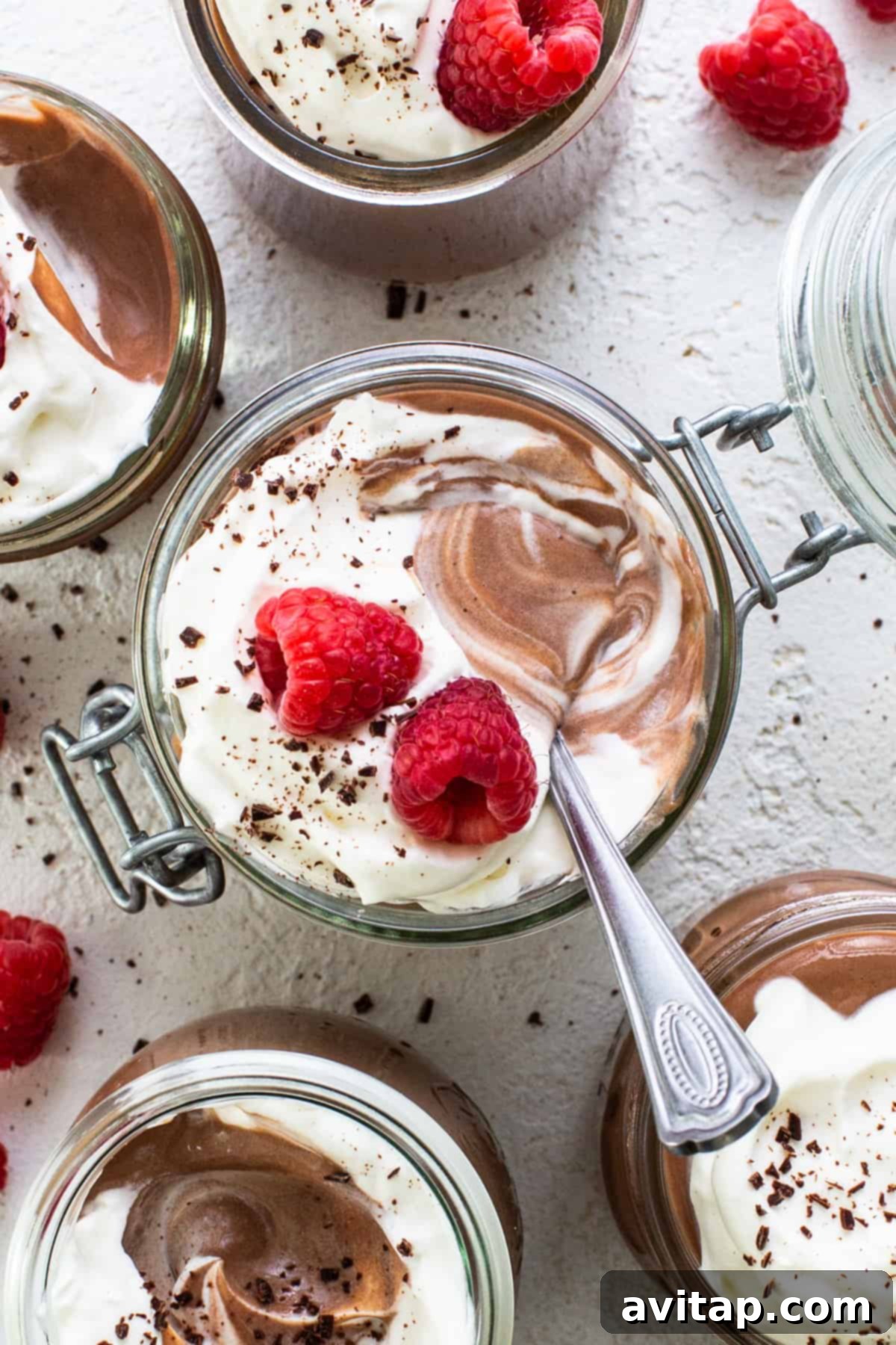 Chocolate mousse in jars with raspberries and whipped cream.
