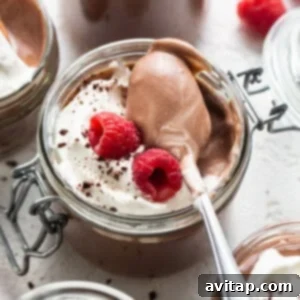 Chocolate mousse in jars with whipped cream and raspberries.