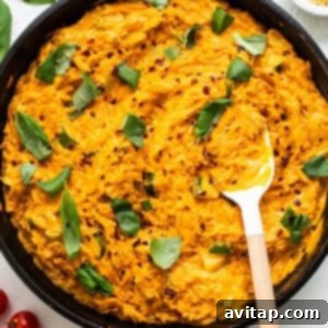 A skillet filled with creamy tomato orzo pasta, garnished with fresh herbs and red pepper flakes.