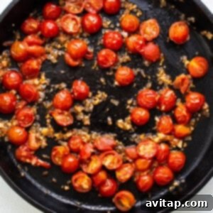 A frying pan full of sautéed tomatoes and onions.