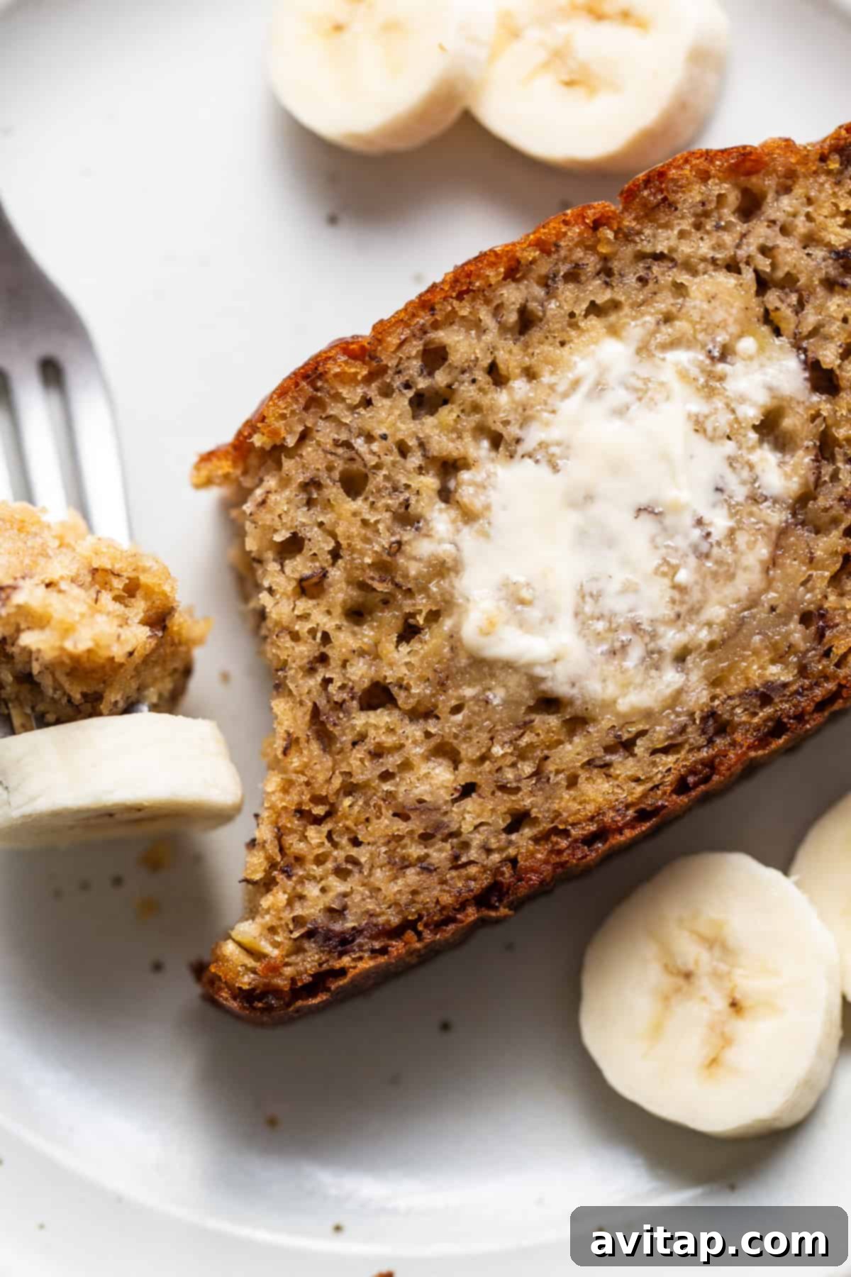 A perfectly sliced piece of protein banana bread on a plate, ready to be enjoyed with a fork.