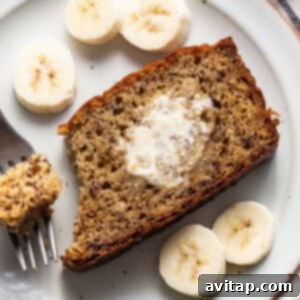 A slice of protein banana bread on a plate with a fork, highlighting its moist texture.