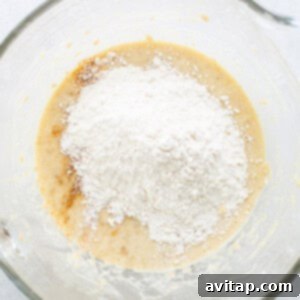 A glass bowl containing flour and sugar, ready for mixing into the batter.