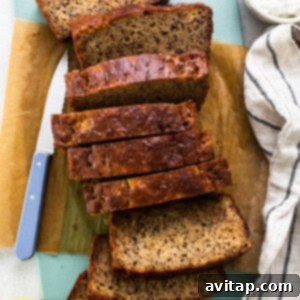 A sliced loaf of banana bread on a cutting board with a knife.