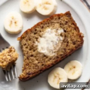 A single slice of protein banana bread on a plate with a fork, ready to eat.
