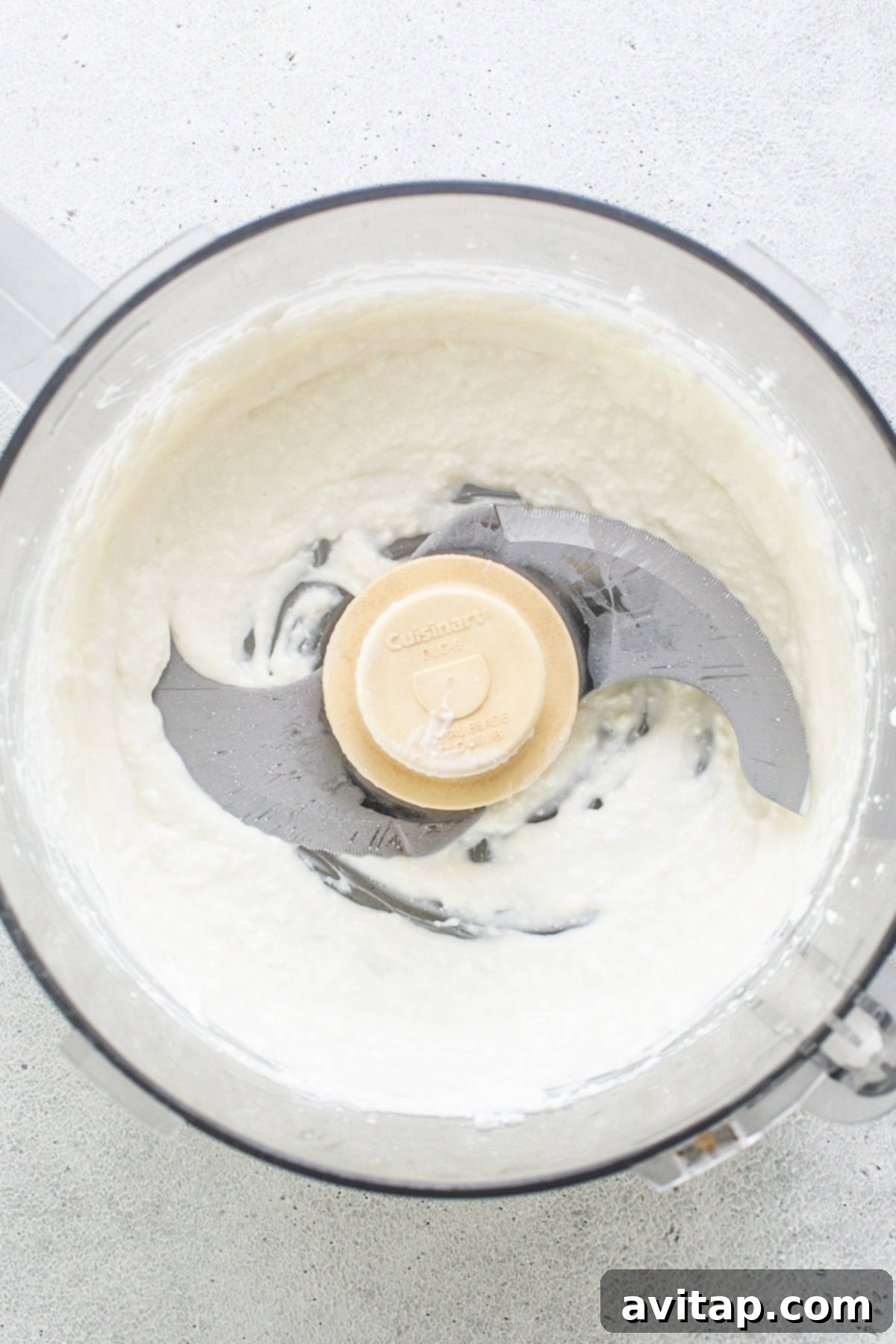 Smooth, creamy blended cottage cheese in a food processor, ready for mixing into the banana bread batter.