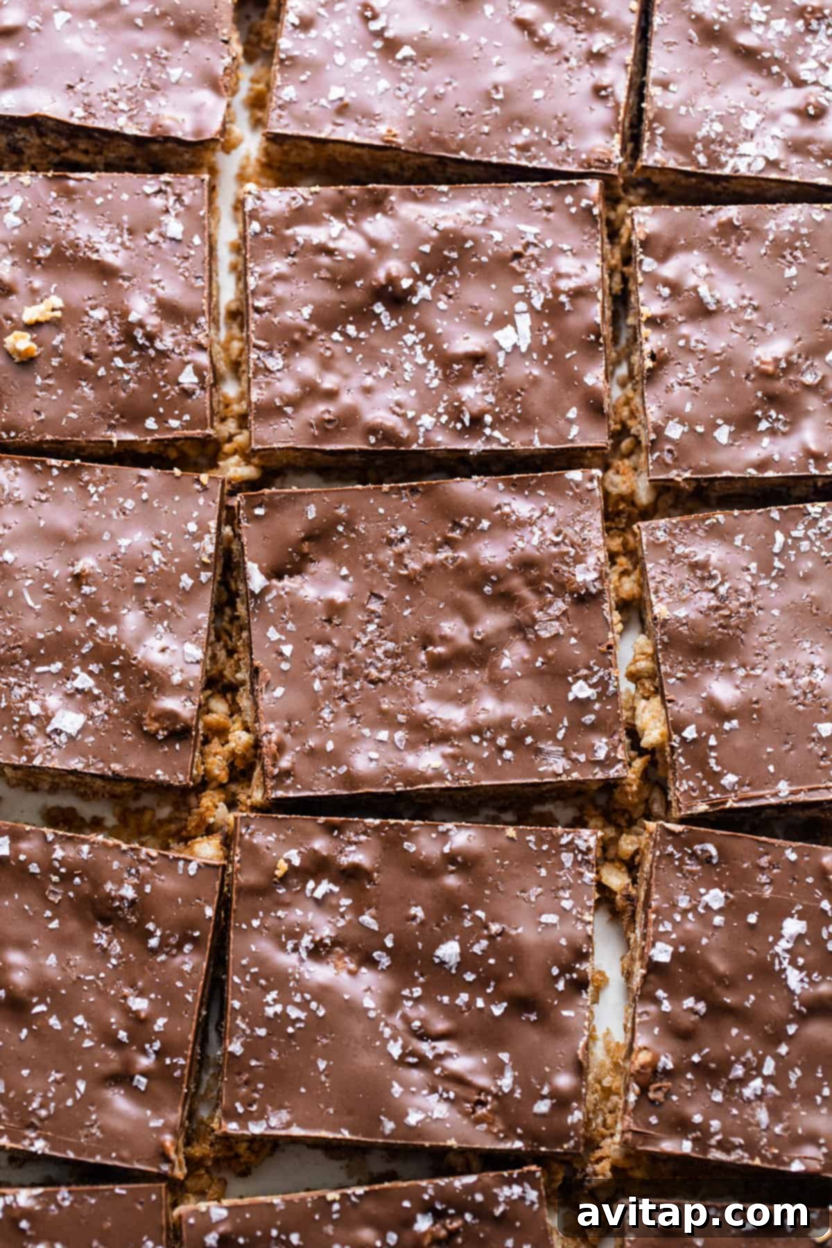 A close-up view of perfectly cut chocolate squares on a white plate, showcasing the finished protein scotcheroos.
