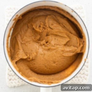Pumpkin butter in a pan with a wooden spoon.