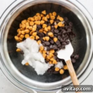 Chocolate chips in a bowl with a wooden spoon.