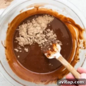 A person mixing chocolate in a bowl with a wooden spoon.