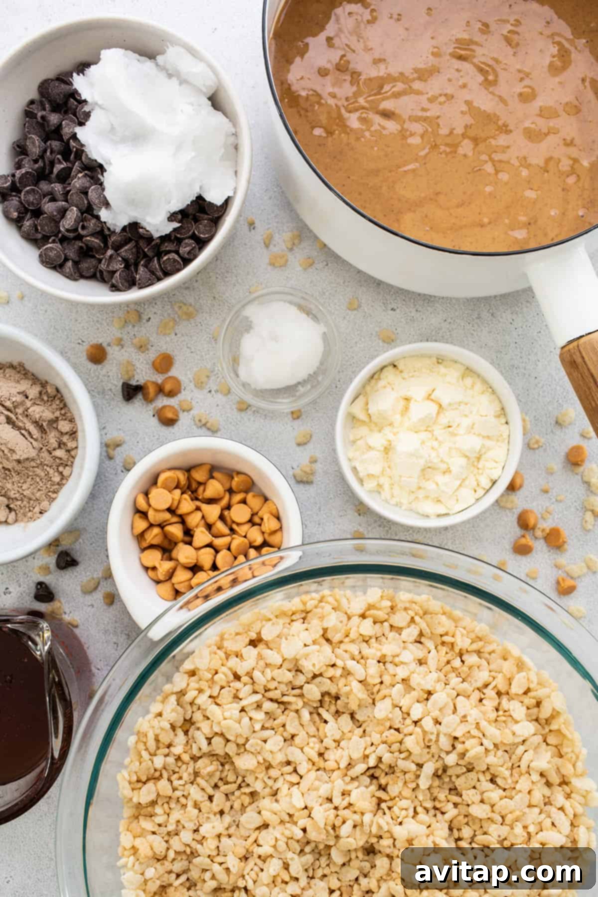 Protein Power Scotcheroos 3 Oats, chocolate chips, peanut butter, and other fresh ingredients artfully arranged in individual bowls on a pristine white background, showcasing the wholesome components of the recipe.