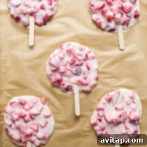 Strawberry yogurt mixture with popsicle sticks on a baking sheet, freezing to solidify.