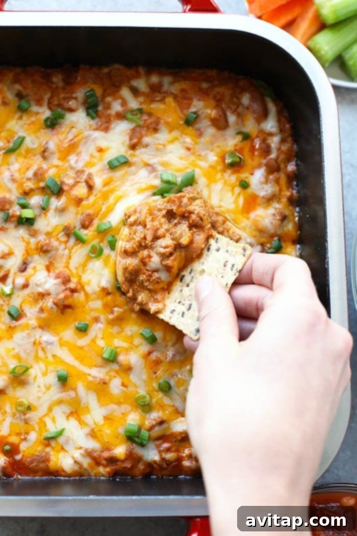 Make this winning chili cheese dip for the big game and your guests will gobble it up. It really is the best chili cheese dip recipe! A chip expertly scooping a generous portion of warm, bubbling chili cheese dip from a baking dish.