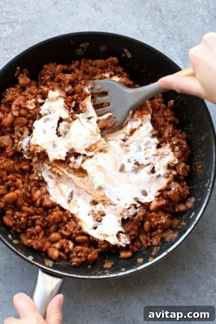 Make this winning chili cheese dip for the big game and your guests will gobble it up. It really is the best chili cheese dip recipe! Sautéed ground turkey, garlic, and onion simmering in a large pan, forming the flavorful base of the chili cheese dip.