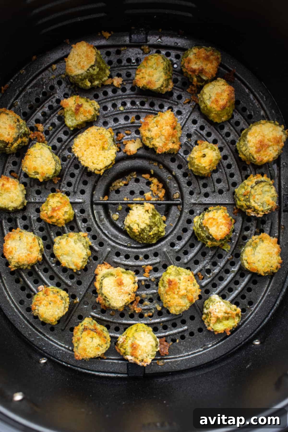 A close-up shot of crispy, golden-brown air-fried pickles fresh out of the air fryer basket.