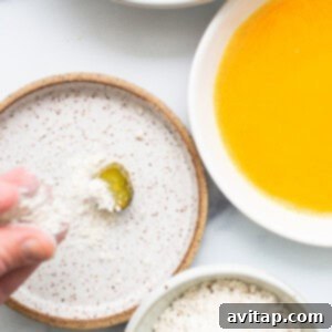 A person is sprinkling flour on a bowl of pickles.
